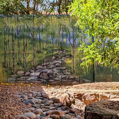 Backyard wall art depicting a scenic mountain range overlooking a calm blue lake.