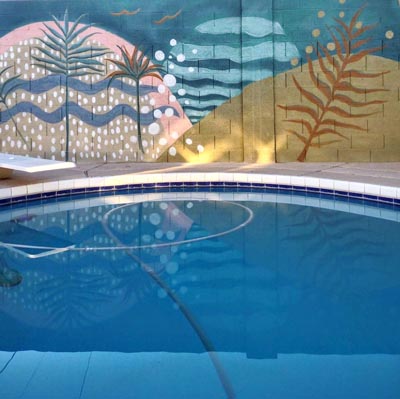 Transformative poolside block wall mural featuring a lush garden and ocean view.