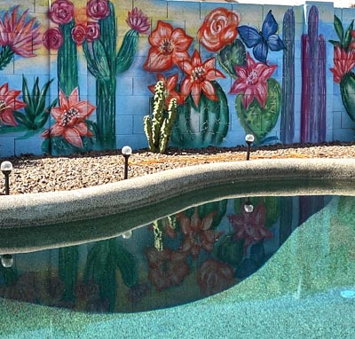 Artistic desert flower and cactus mural painted on a poolside block wall.